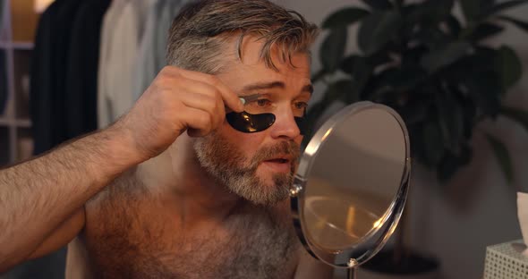 Handsome Mature Bachelor Plucking Eyebrows While Sitting in Front of mirror, Bearded Guy in 40s 