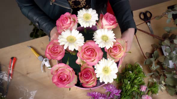 Close-up of the hands of a female florist packing a beautiful composition