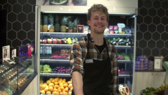 Portrait Shot of the Young Handsome Caucasian Shop Worker in the Apron in Front the Camera and