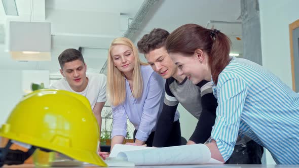 Group of Young Engineers Discussing Architectural Blueprints