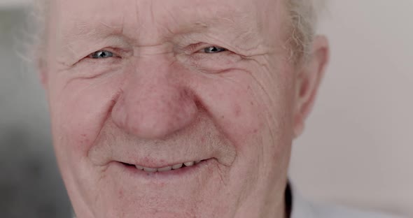 Happy Cured Senior Man Smiling Into Camera and Putting Medical Mask on Ear