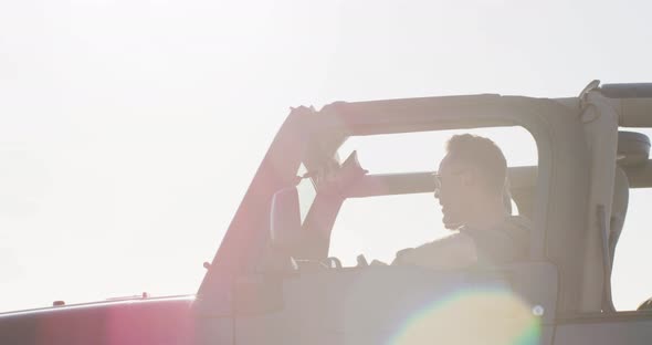 Happy caucasian gay male couple in car admiring the view and pointing on sunny day at the beach