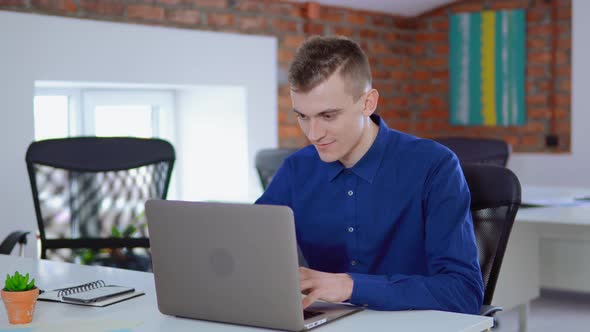 Businessman Sitting at the Desk, Using Laptop, Finishes Project