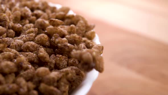 Full white bowl of chocolate crunchy dry rice flakes on a wooden surface