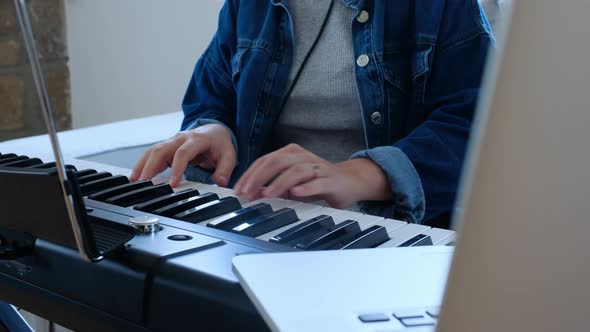 Young woman playing electronic piano at home