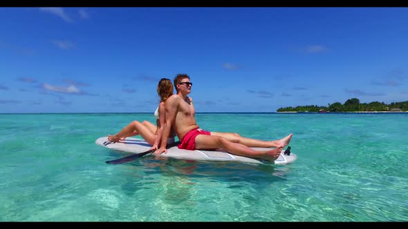 Two lovers sunbathe on relaxing coastline beach break by blue lagoon and white sandy background of t