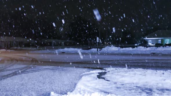 Giant snowflakes falling across a parking lot through the street lights at night.