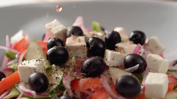 Camera follows putting dressing over greek salad. Slow Motion. alt