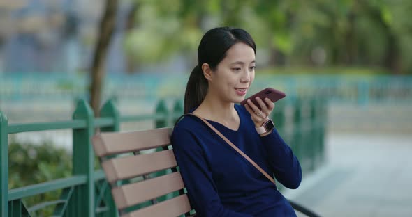 Young Woman work on mobile phone and sit on the bench