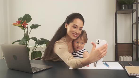 Mom and Her Little Daughter Take Selfies While Working in the Home Office