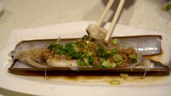 Using Chopsticks To Eat Baked Razor Calm With Glass Noodle In Chinese Food Restaurant