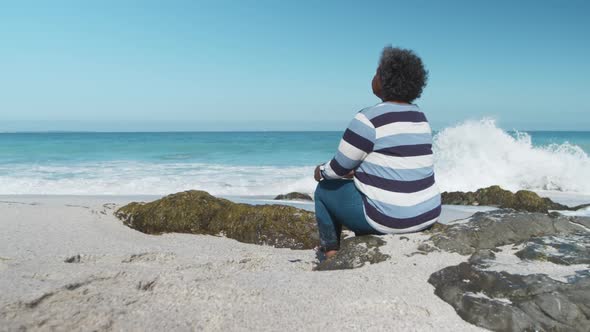 Senior woman sitting on a rock at the beach