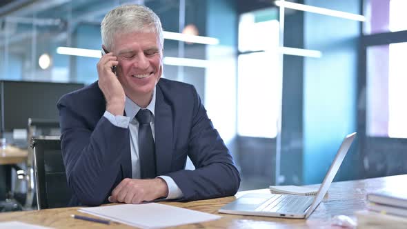 Cheerful Middle Aged Businessman Talking on Cellphone