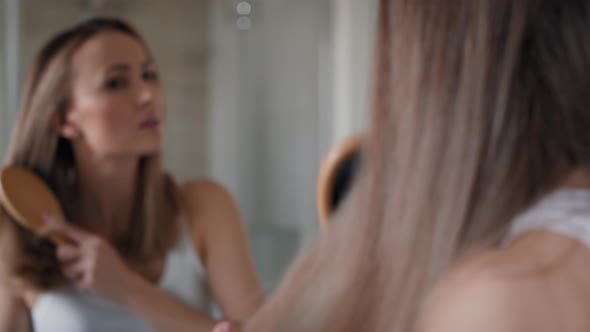 Caucasian woman brushing hair in the bathroom. Shot with RED helium camera in 8K.