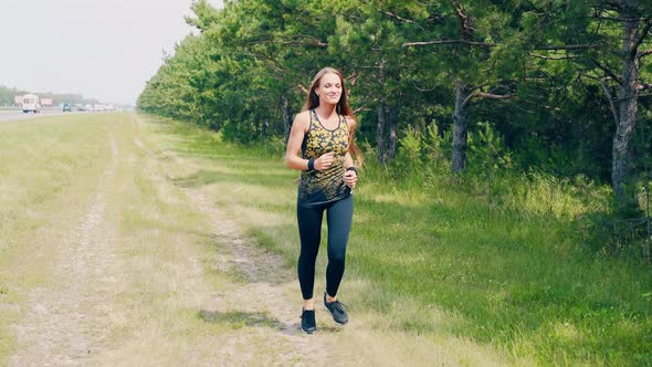 Young Girl Goes in for Sports in the Morning, Runs Along a Pine Forest and Trails