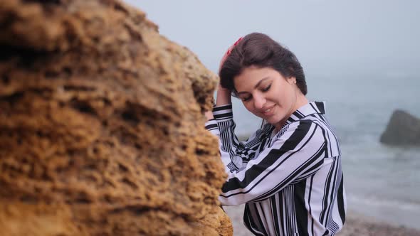 Beautiful Young Woman Stands at Rock Resting