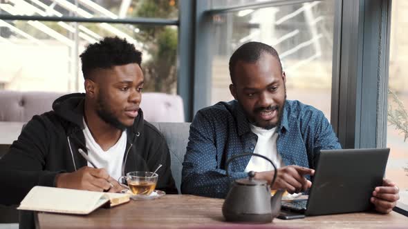 Two Young African American Male Friends Sitting Together in Cafe