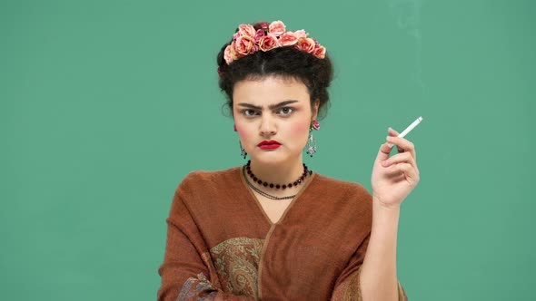 Portrait of Serious Woman with Thick Eyebrows As Artist Frida Kahlo with Flowers in Hair Looking