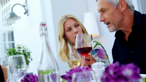 Friends interacting with each other while having glass of wine