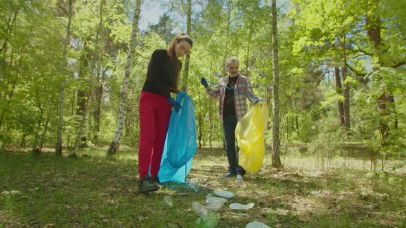 Environmental Aware Volunteers Gathering Litter During Cleaning in Woodland