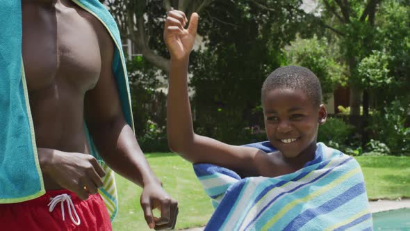 Happy african american father and son wiping with towels at pool