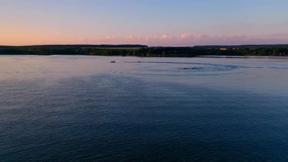 Boat sailing at sunset. Evening river landscape on industrial factory background.