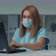 Young Woman Puts a Medical Mask on Her Face and Works at a Laptop in the Office - VideoHive Item for Sale