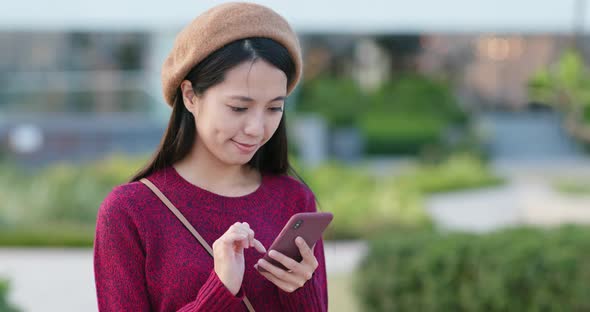 Woman work on mobile phone in city park