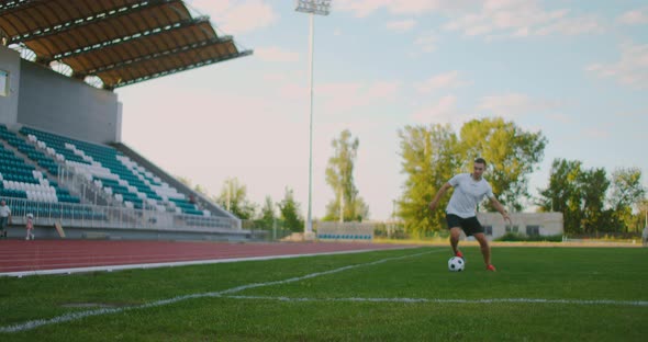 A Professional Football Player in Uniform on the Football Field of the Stadium Makes a Kick