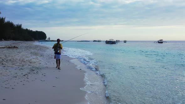 Angling for Happy man on a journey spends quality time at beach on sunny blue and white sand 4K back