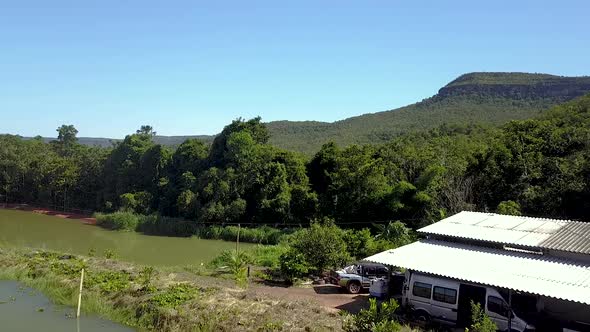 Drone flying low over a fish farm in the Tocantins region of Brazil with mountains along the horizon