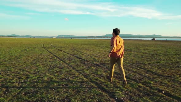 slow-motion of cheerful man running across the green field with sunlight