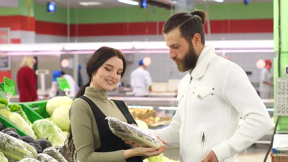 Beautiful Young Smiling Couple Choosing Cauliflower in Supermarket Together