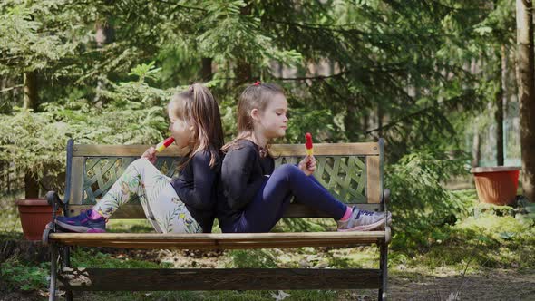 Two Sisters Are Eating Ice Cream in Spring Forest