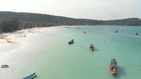 Shoreline circling around shallow bay with fisher boats moored in Saracen Bay in Koh Rong Sanloem