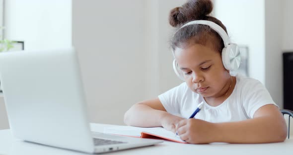 Afro American Kid Girl School Pupil Wearing Headphones Studying Online From Home Watching Web Class