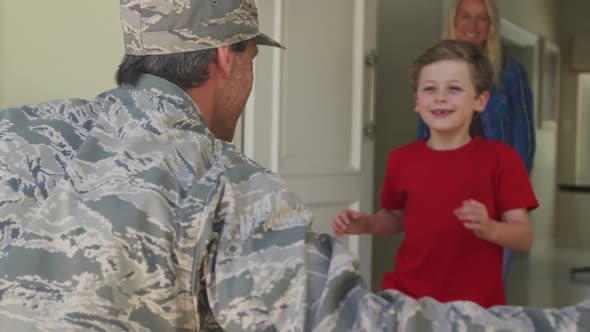 Caucasian male soldier embracing his smiling son over smiling wife and american flag