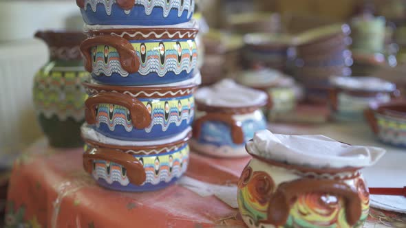 Close Up of Rows and Shelves of Various Colorful Clay Pottery Jars Bowls and Cups