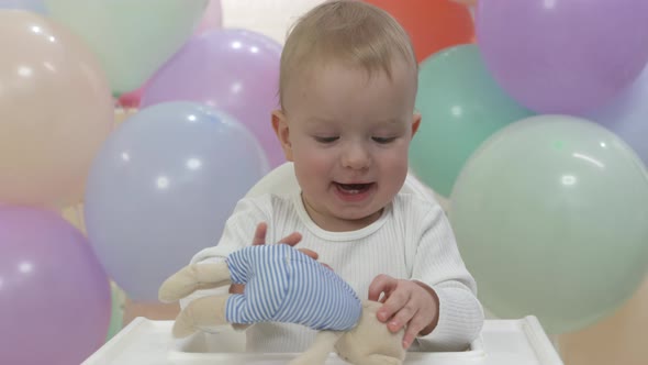 Happy Baby Boy Playing with a Toy at His First Birthday Party Oneyearold Child Against the