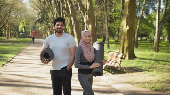 Front View of Smiling Muslim Man and Charming Woman in Hijab Standing Together