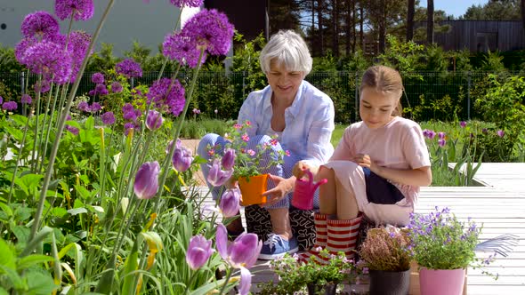 Grandmother and Girl Planting Flowers at Garden 