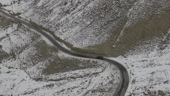 Aerial shot of car on the street with snow caped mountain in the side. Karakoram Highway through Khu