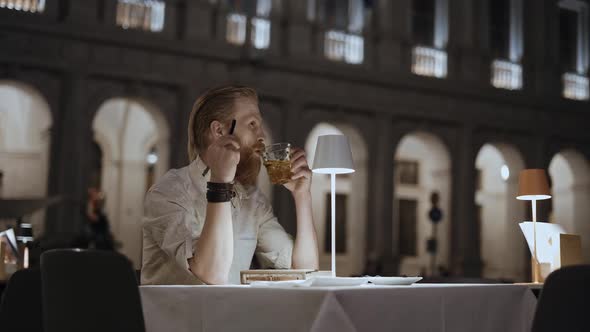 An Elegant Businessman with a Notebook a Tourist with a Beard Having Dinner on the Terrace