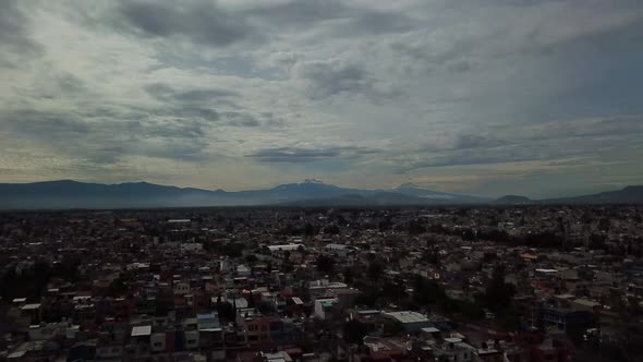 Aerial drone shot of Mexico city and Popocateptl cloudy day, drone foward