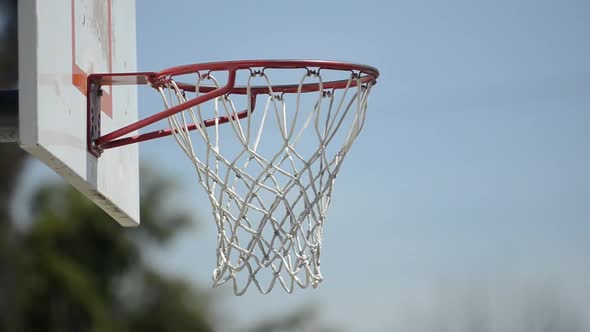 Extreme closeup of a man slam dunking a basketball on a playground court.