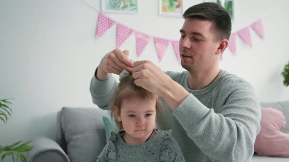 Fatherhood Loving Caring Male Parent Does His Daughter Hair and Ties Her Hair Up with an Elastic