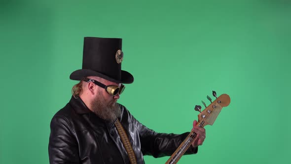 Bearded Man in Long Leather Coat an Irish Style Hat and Original Glasses Plays the Red Guitar