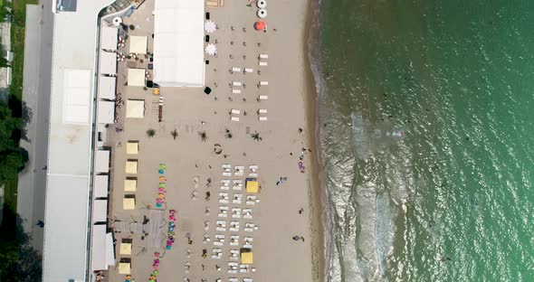 Top down view of sandy beach full of people. Sunny day. People rest and sunbathe on the beach.