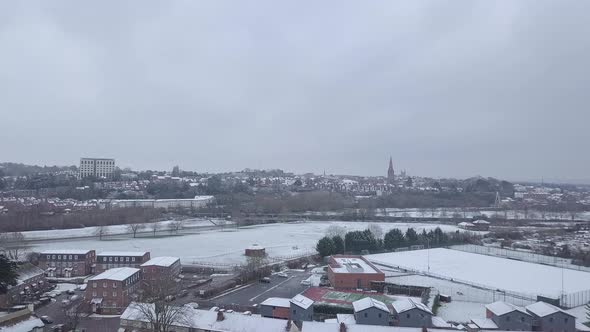 High dolly forward drone shot of a snowy Exeter as a train passes by
