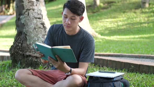 Male Student Reading Book In A Park